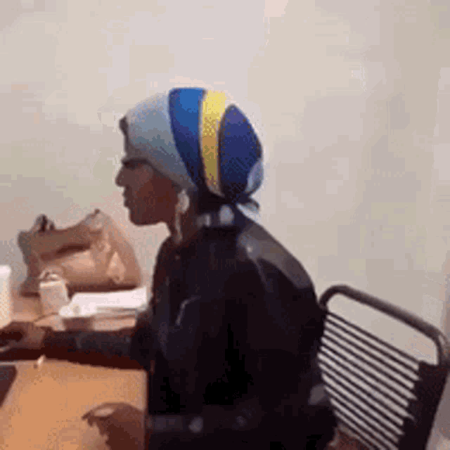 a woman wearing a head scarf sits at a desk