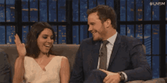 a man and a woman are sitting on a couch clapping their hands