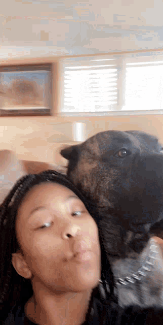 a girl with braids is taking a selfie with a dog
