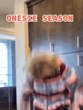 a person wearing a plaid shirt is dancing in a room with the words onesie season written on the bottom .