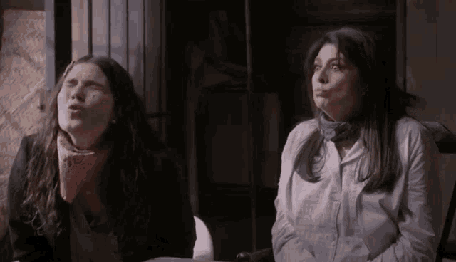 two women are sitting next to each other in a dark room .