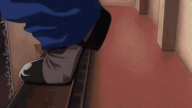 a person is walking down a hallway with a red carpet .