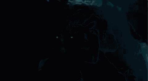 a man in a suit is standing in a dark room with his eyes glowing .