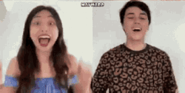 a man and a woman are standing next to each other with their mouths open and their hands in the air .