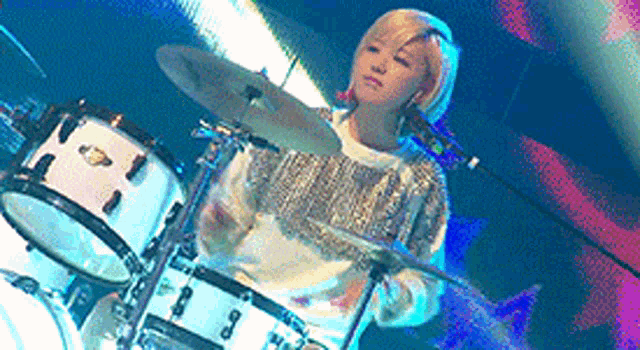 a woman is playing drums in front of a microphone on a stage