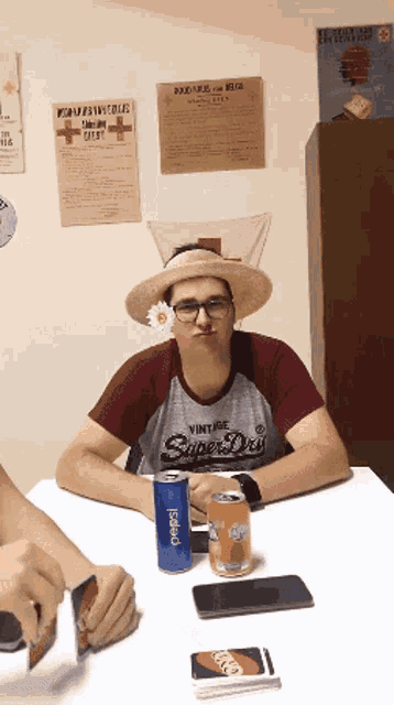 a man wearing a vintage super dry shirt sits at a table with a can of pepsi