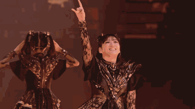 a woman in a black and gold dress is giving the peace sign