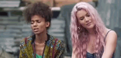 two women with pink hair are sitting next to each other and talking .