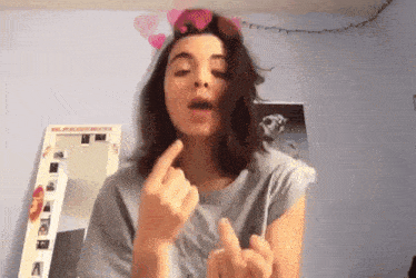 a girl giving the middle finger in front of a mirror with a picture of a man on it