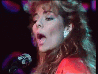 a woman singing into a microphone with her mouth wide open