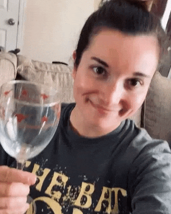 a woman in a t-shirt is holding a wine glass and smiling .