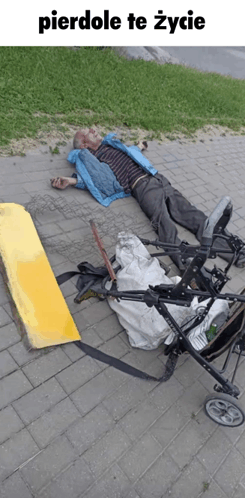 a man in a blue jacket is laying on the ground next to a stroller and a ramp