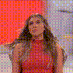 a woman in a red top is standing in front of a red wall .