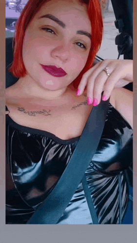 a woman with red hair is sitting in a car wearing a black leather top .