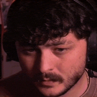 a man with a beard wearing headphones is looking at the camera .