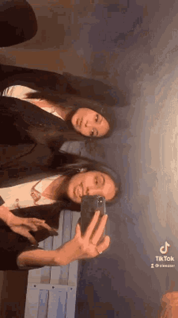 two women are taking a selfie together with their phones .