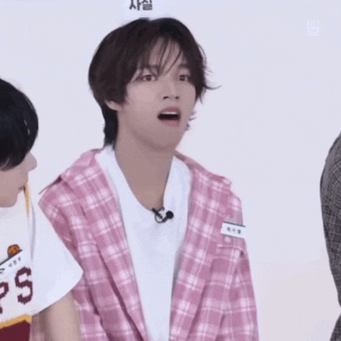 a young man wearing a pink plaid jacket and a white t-shirt with ps on it