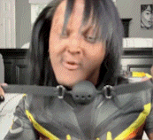a woman is wearing a batman costume with a gag around her mouth