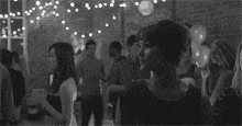 a group of people are dancing in a room with balloons .