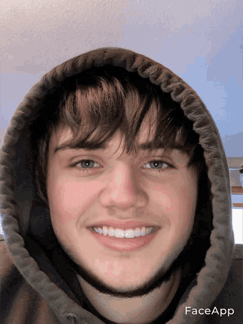 a young man wearing a hooded sweatshirt is smiling for the camera with faceapp displayed on the bottom right