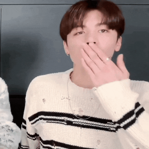 a young man in a sweater is blowing a kiss .