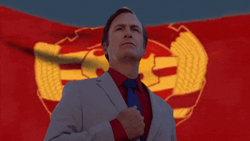 a man in a suit and tie stands in front of a red flag with chinese characters