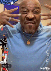 a man wearing a blue shirt and a gold necklace is making a face