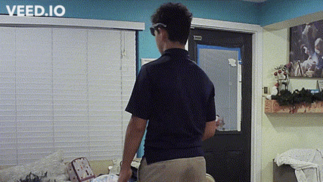 a man in a blue shirt is standing in a room with a sign that says veed.io