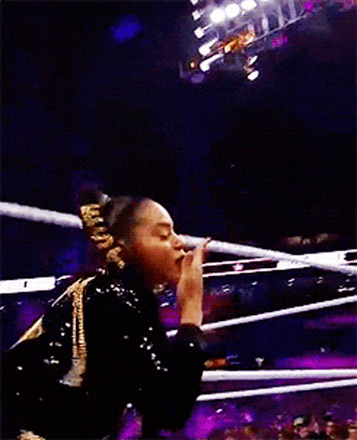 a woman in a black and gold outfit is standing in a ring
