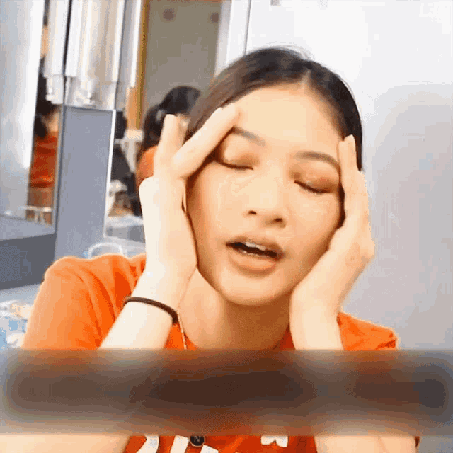a woman with her eyes closed holds her hands to her face