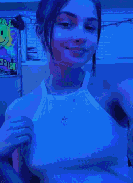 a girl wearing a white tank top is smiling in front of a poster that says ' aloe ' on it