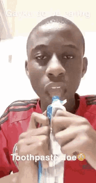 a young man is brushing his teeth with toothpaste .