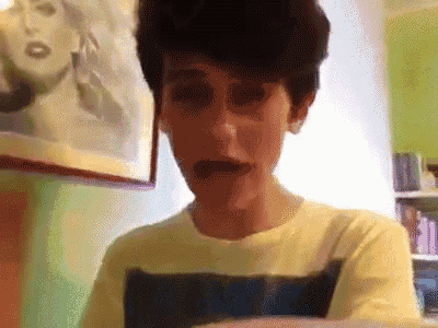 a man in a yellow shirt is making a funny face in front of a picture of a woman