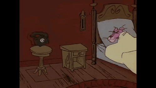 a pink panther is laying in a bed next to a phone