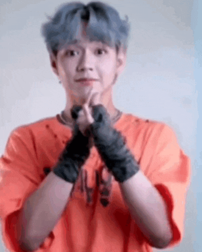 a young man wearing boxing gloves and an orange shirt is making a heart with his hands .