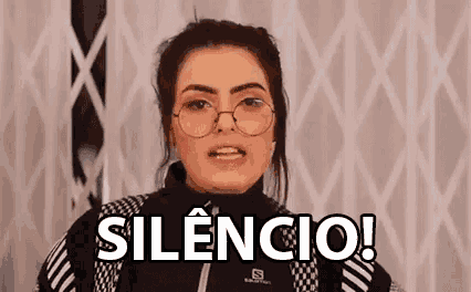 a woman wearing glasses and a black jacket is making a funny face and says silencio !