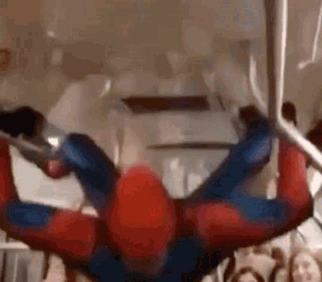 a man in a spiderman costume is hanging upside down from a rope .