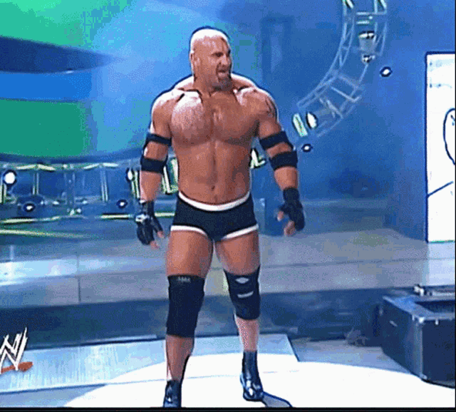 a shirtless wrestler is standing in front of a sign that says wwe on it