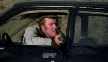 a man is sitting in a car holding a gun in his hand .