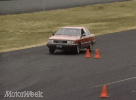 a red car is driving down a road and the words motorweek are on the bottom