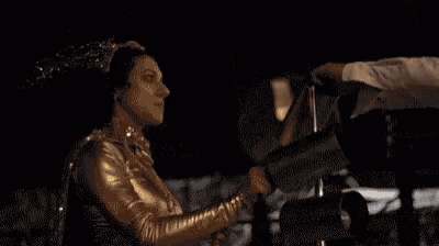 a woman in a gold outfit is holding a flashlight in her hand .