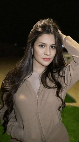 a woman with long dark hair is wearing a brown jacket