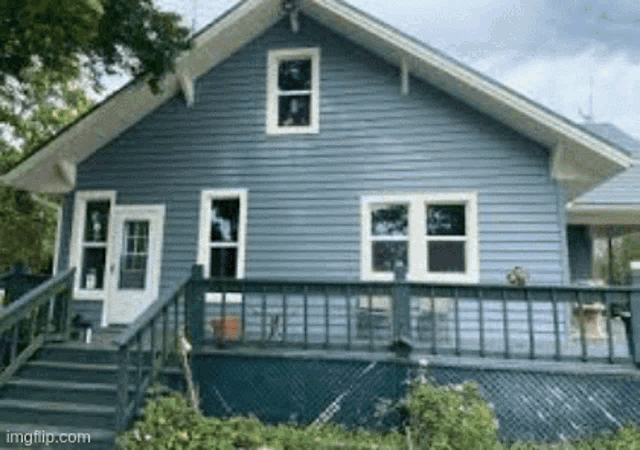 a blue house with white trim and a green deck
