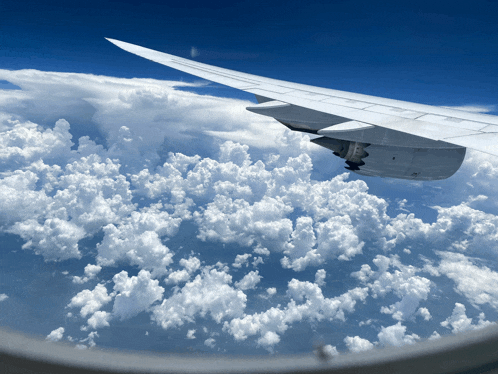 the wing of an airplane is visible flying through the clouds