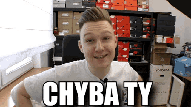 a man in a white shirt is smiling in front of a shelf full of shoes and a box that says volteno