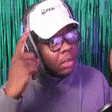 a man wearing glasses and a baseball cap is talking on a cell phone .