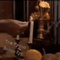 a person is holding a candle in front of a candle holder with candles in it .