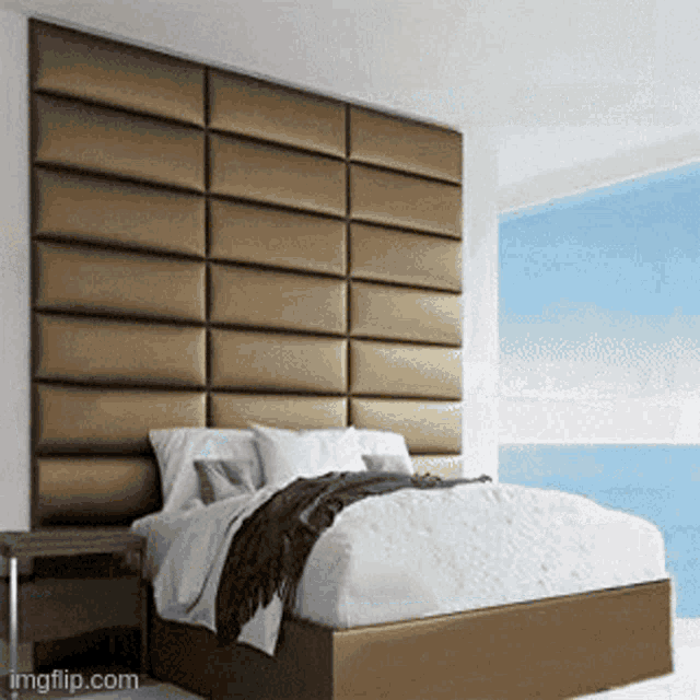 a bed in a bedroom with a large headboard and a large window