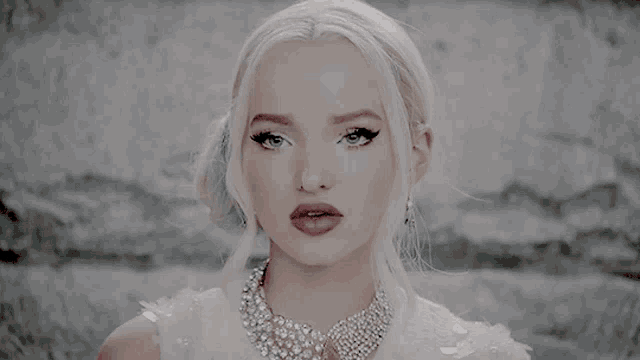 a woman with blonde hair wearing a white dress and a necklace with rhinestones