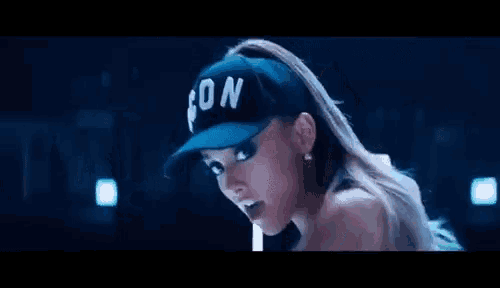 ariana grande is wearing a baseball cap and a ponytail .
